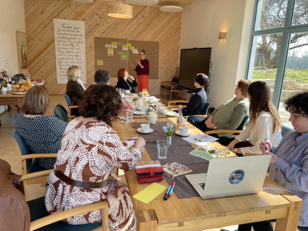 An einer Besprechung teilnehmende Mitarbeiter an einem großen Tisch